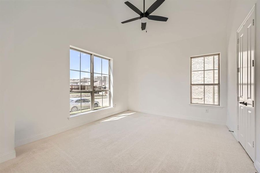 Empty room featuring light carpet, ceiling fan, and a wealth of natural light