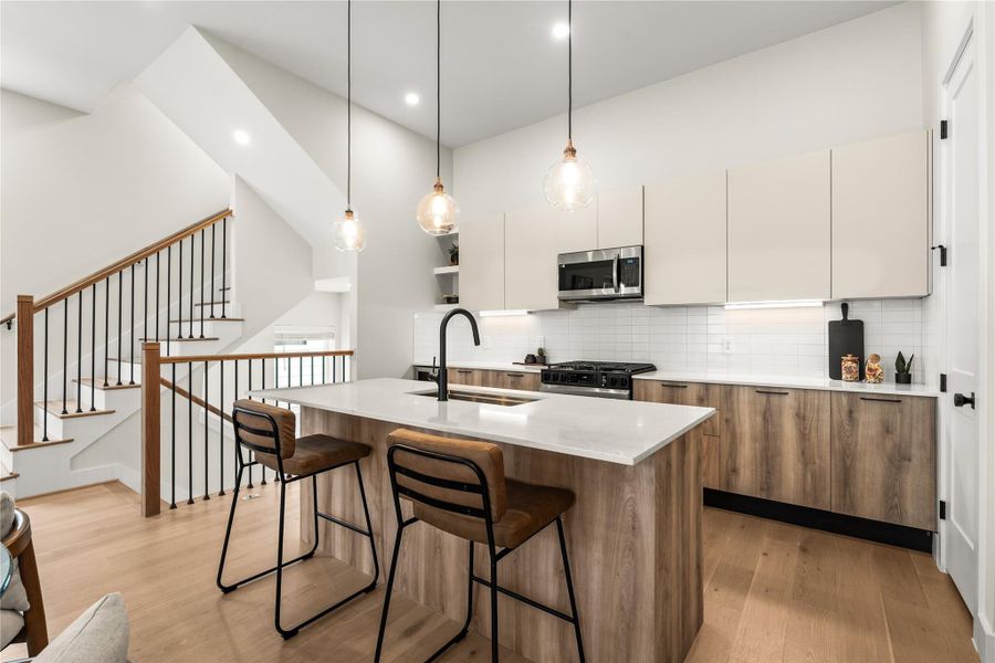 The island adds casual counter seating and workspace, complemented by extensive cabinetry along the kitchen’s full rear wall.