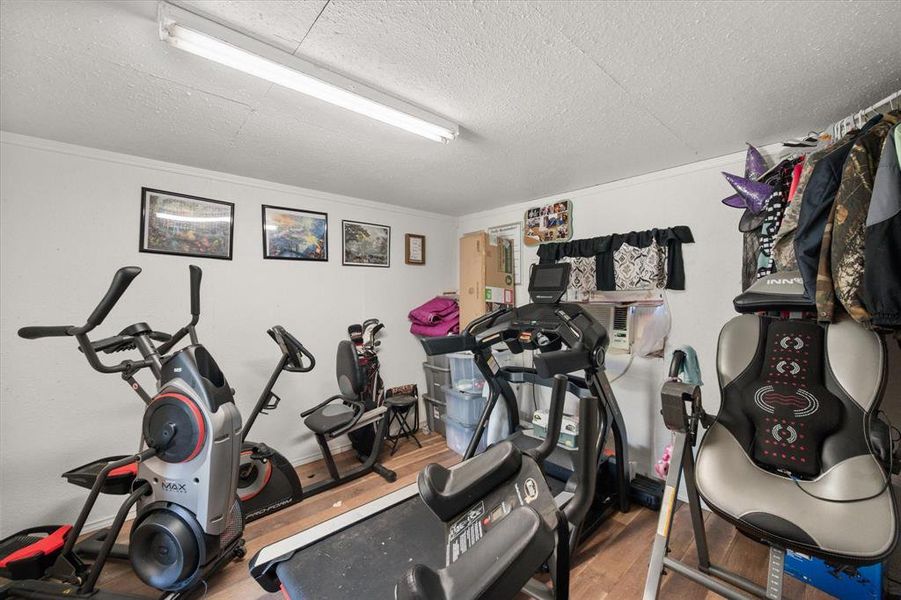 Workout room with a textured ceiling, wood finished floors, and ornamental molding Workout room with a textured ceiling, wood finished floors, and ornamental molding