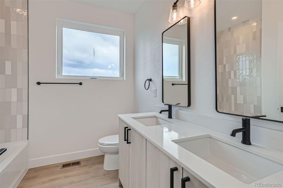 Large full bathroom on 3rd level with double vanity, quartz countertops, tub, and shower(NOTE: This home has a darker color scheme. See finishes for details.)