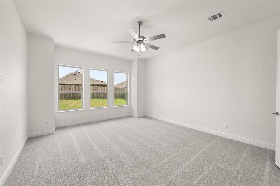 Carpeted empty room with ceiling fan and baseboards