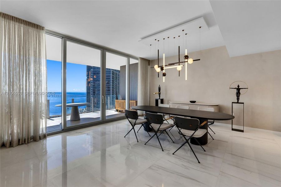 Floor-to-ceiling glass sliding doors, polished stone-finish flooring, custom modern linear pendant lighting, and an expansive covered balcony