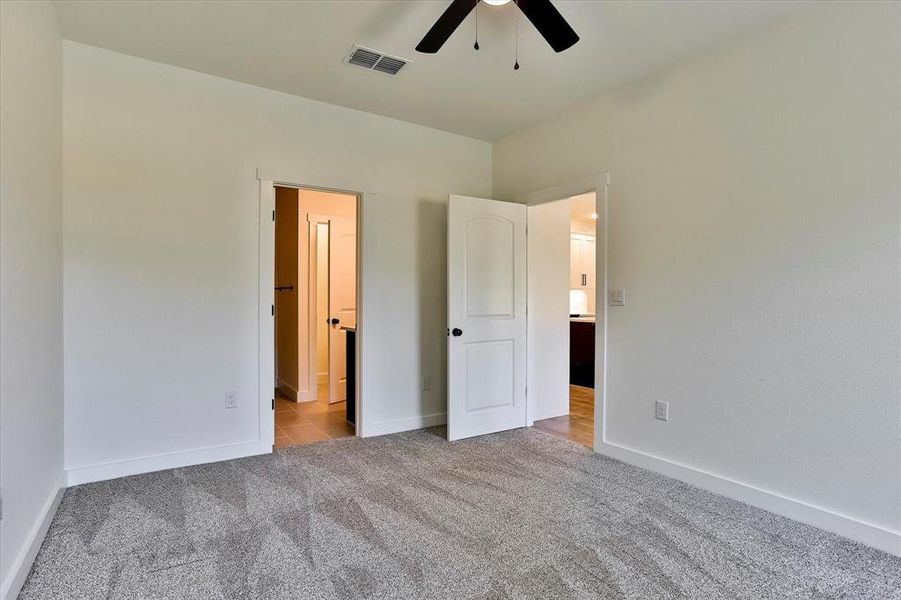 Unfurnished bedroom with ceiling fan and light colored carpet