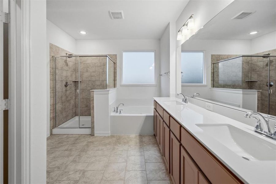 Full bath featuring a stall shower, double vanity, and a garden tub