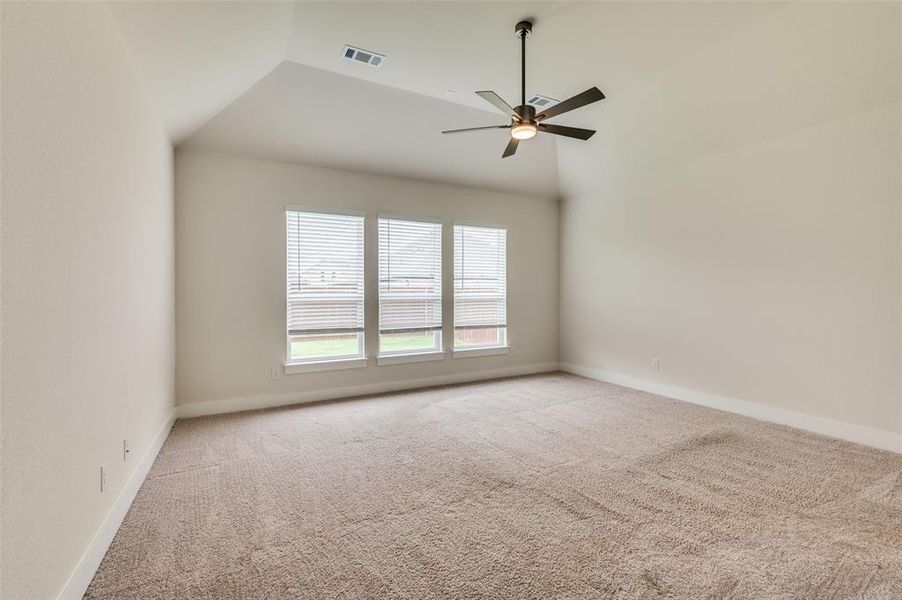 Carpeted spare room with lofted ceiling, ceiling fan, and baseboards Carpeted spare room with lofted ceiling, ceiling fan, and baseboards