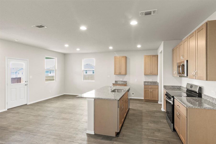 Kitchen with appliances with stainless steel finishes, a kitchen island with sink, recessed lighting, light stone counters, and dark wood-type flooring