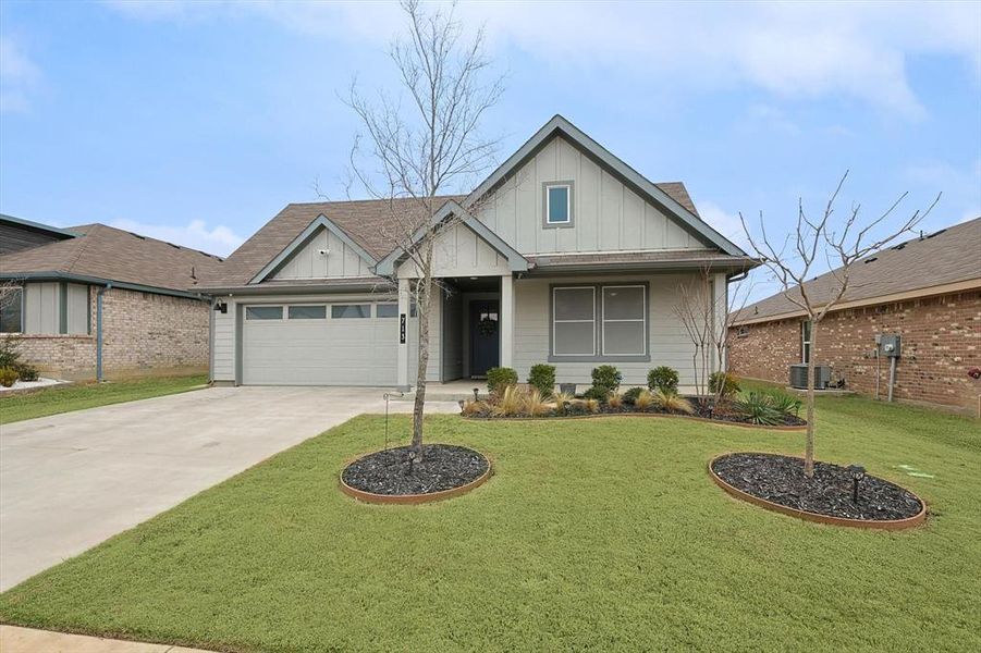 View of front of house with driveway, an attached garage, board and batten siding, and a front yard