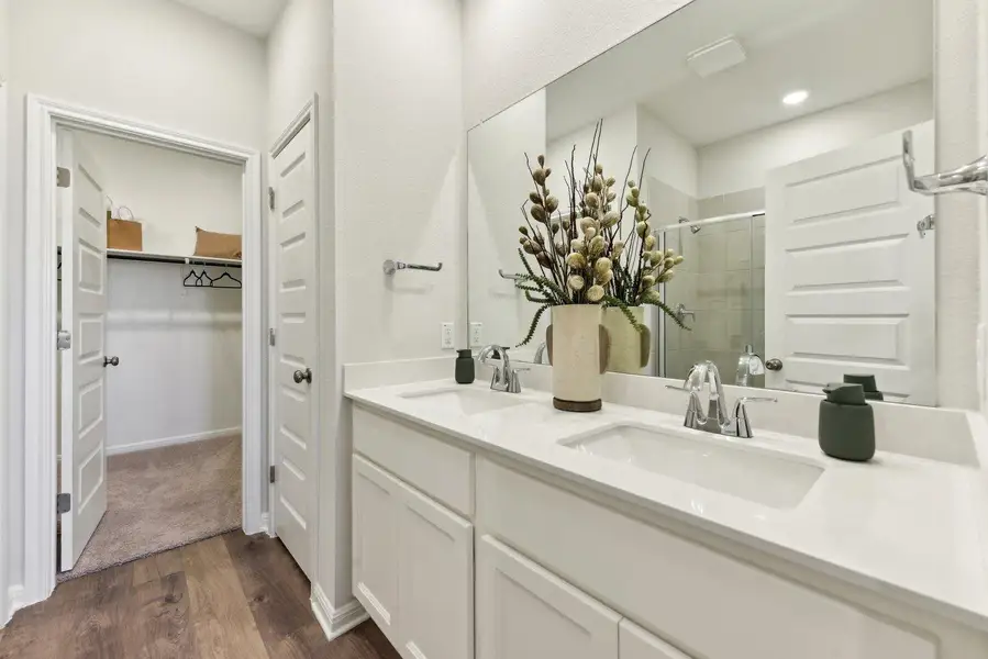 Double vanity with pristine counters offers convenient bathing adjacent to a spacious walk-in closet.