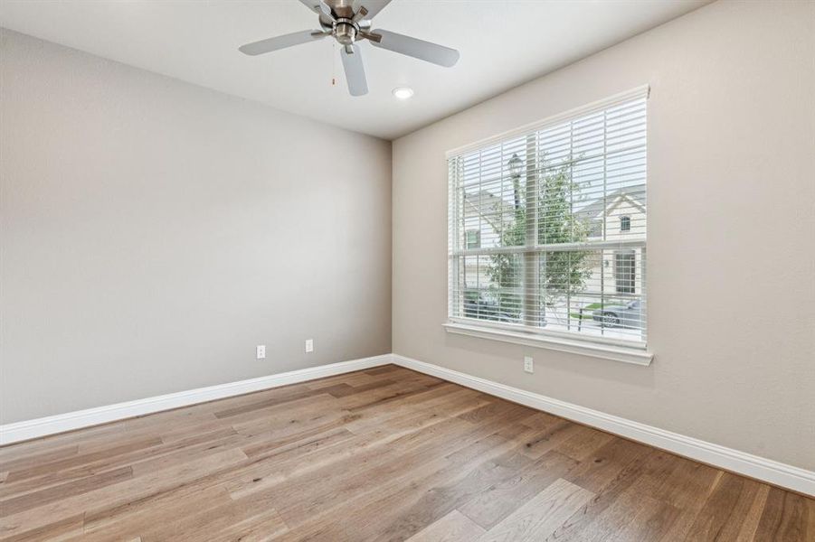 Unfurnished room with healthy amount of natural light, light wood-style floors, and ceiling fan