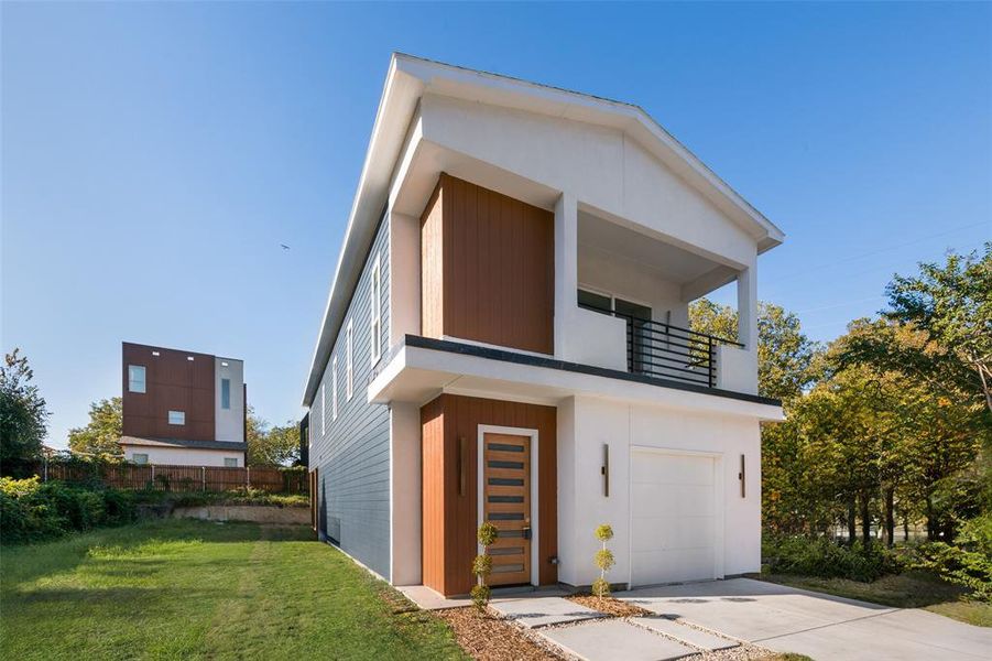 View of front facade with a balcony, an attached garage, and concrete driveway View of front facade with a balcony, an attached garage, and concrete driveway