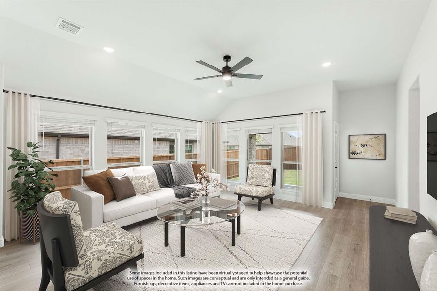 Living room with vaulted ceiling, ceiling fan, hardwood floors, and large windows with backyard views