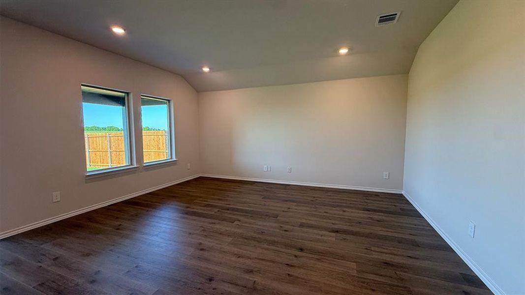 Spacious room featuring wood-finish flooring, two windows, recessed lighting, and neutral wall tones