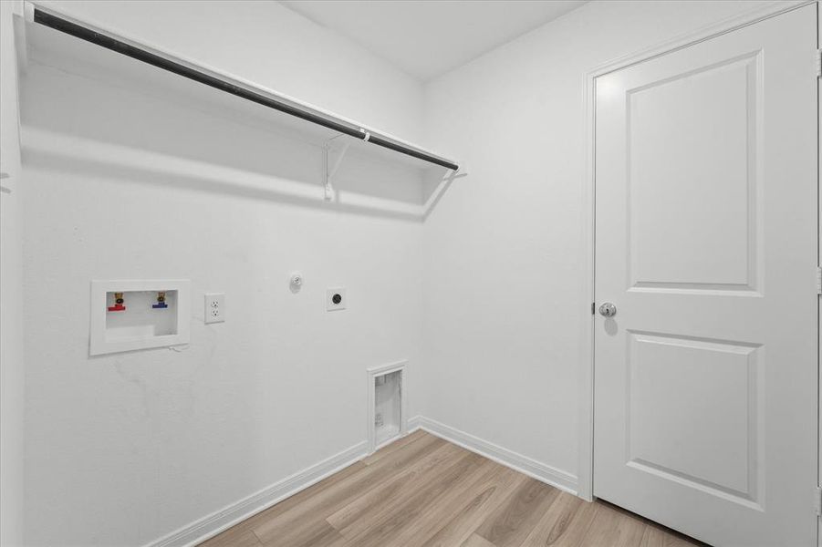 Clothes washing area with light hardwood / wood-style floors, electric dryer hookup, hookup for a gas dryer, and washer hookup