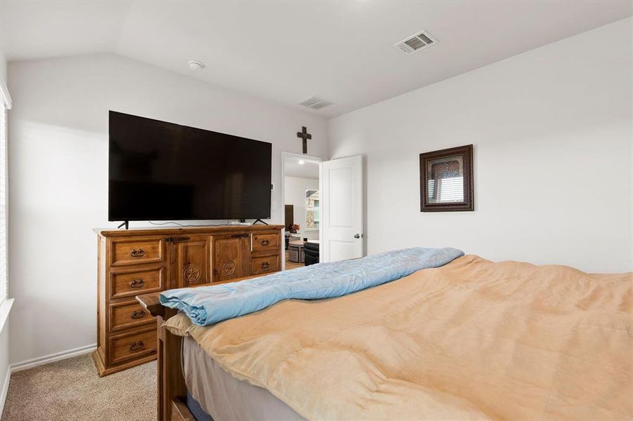 Bedroom featuring light carpet and vaulted ceiling Bedroom featuring light carpet and vaulted ceiling