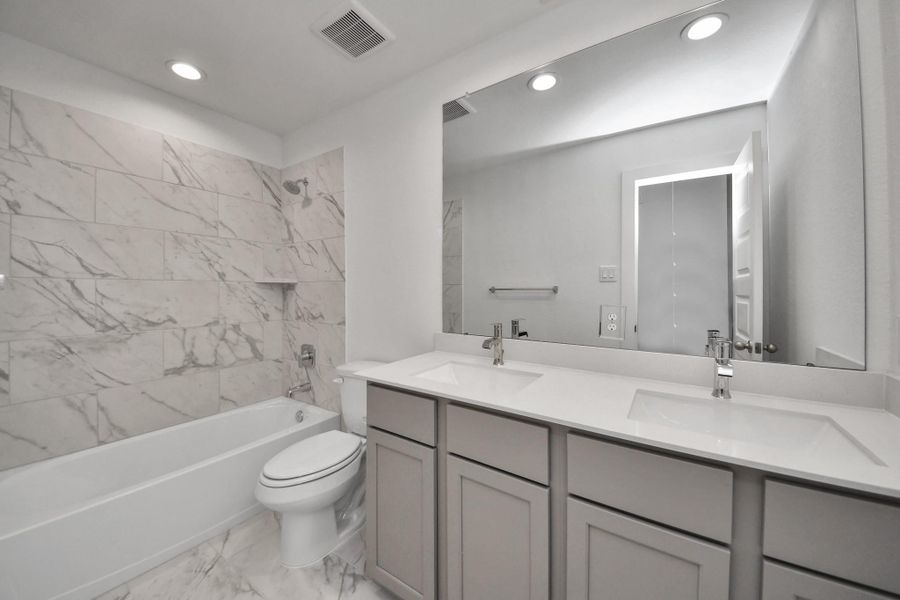 Secondary bath features tile flooring, bath/shower combo with tile surround, light stained wood cabinets, beautiful light countertop. Secondary bath features tile flooring, bath/shower combo with tile surround, light stained wood cabinets, beautiful light countertop.