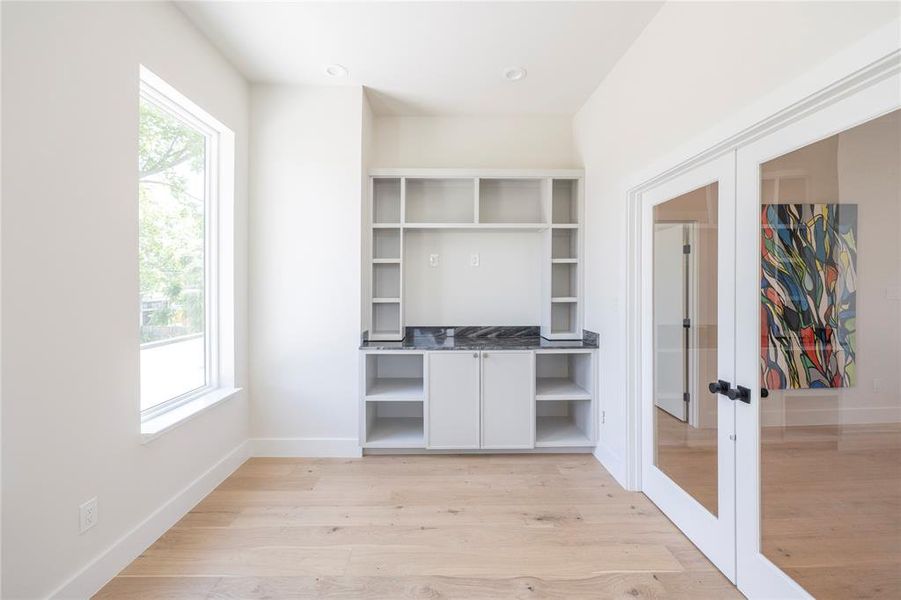 Unfurnished office with light wood-type flooring and french doors