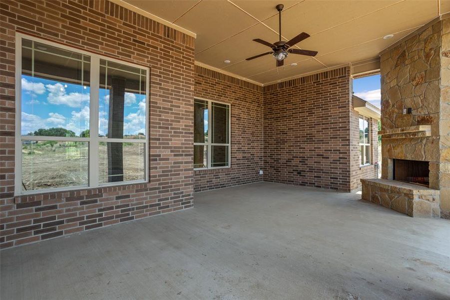 View of patio / terrace with an outdoor stone fireplace and ceiling fan