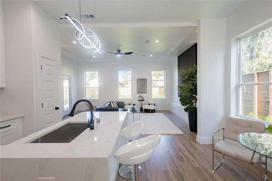 Kitchen with light wood-type flooring, hanging light fixtures, open floor plan, light stone counters, and a ceiling fan Kitchen with light wood-type flooring, hanging light fixtures, open floor plan, light stone counters, and a ceiling fan