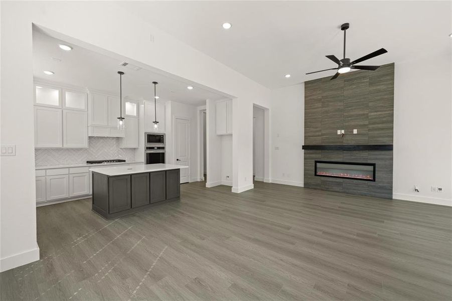 Kitchen with open floor plan, a center island, ceiling fan, stainless steel appliances, and decorative light fixtures