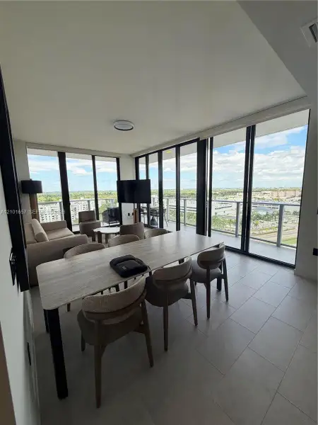 Floor-to-ceiling windows with panoramic exterior exposure, tile flooring, and access to a private balcony