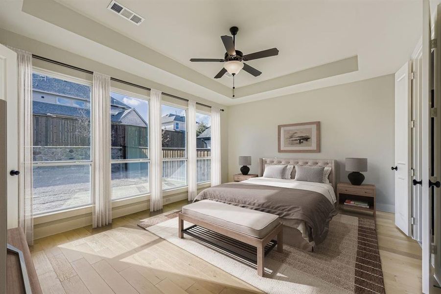 Virtually staged photo - Bedroom featuring light wood-style flooring, a tray ceiling, and a ceiling fan