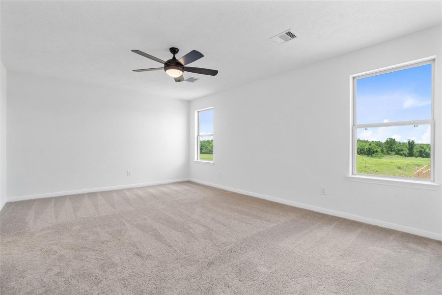 Come and unwind after a long day in this magnificent primary suite! This spacious room features plush carpet, neutral paint, high ceiling with ceiling fan, and large windows.