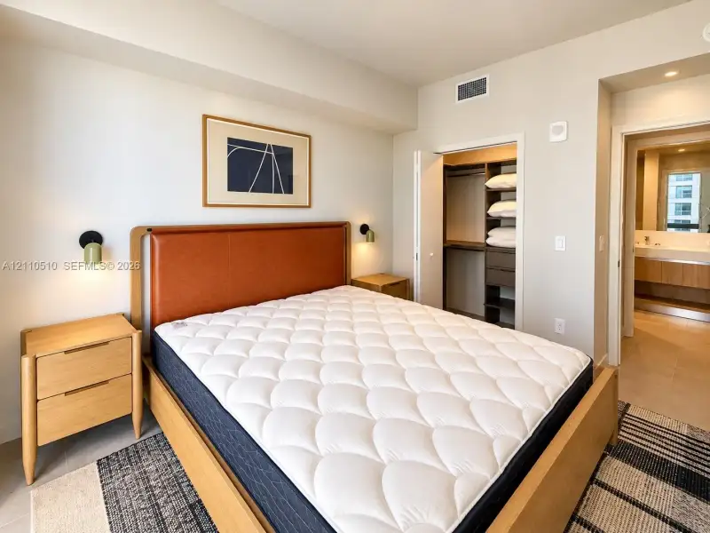 Bedroom featuring recessed lighting, wall-mounted sconces, and an integrated closet system with built-in shelving and drawers Bedroom featuring recessed lighting, wall-mounted sconces, and an integrated closet system with built-in shelving and drawers