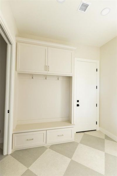 Built-in mudroom cabinetry with upper storage, coat hooks, and a bench with two lower drawers