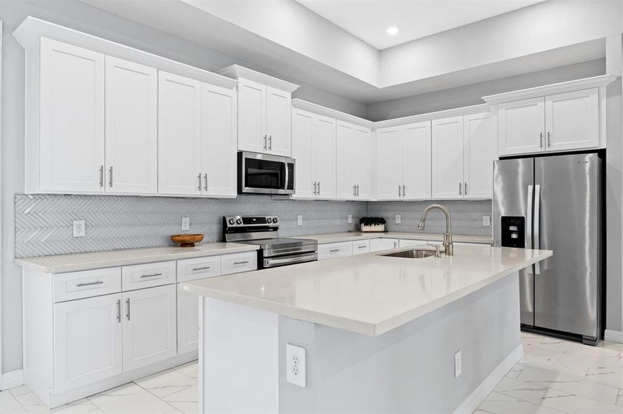 Expansive kitchen with plenty of cabinetry, a large island with a sink, and modern finishes