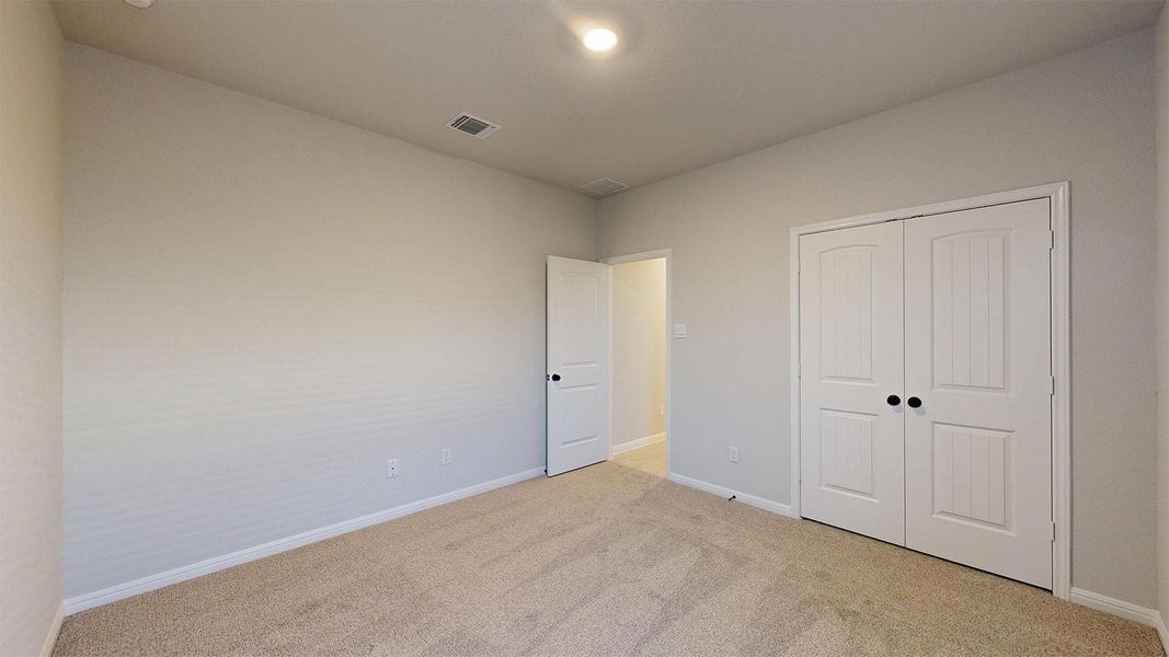 Unfurnished bedroom with light colored carpet and a closet