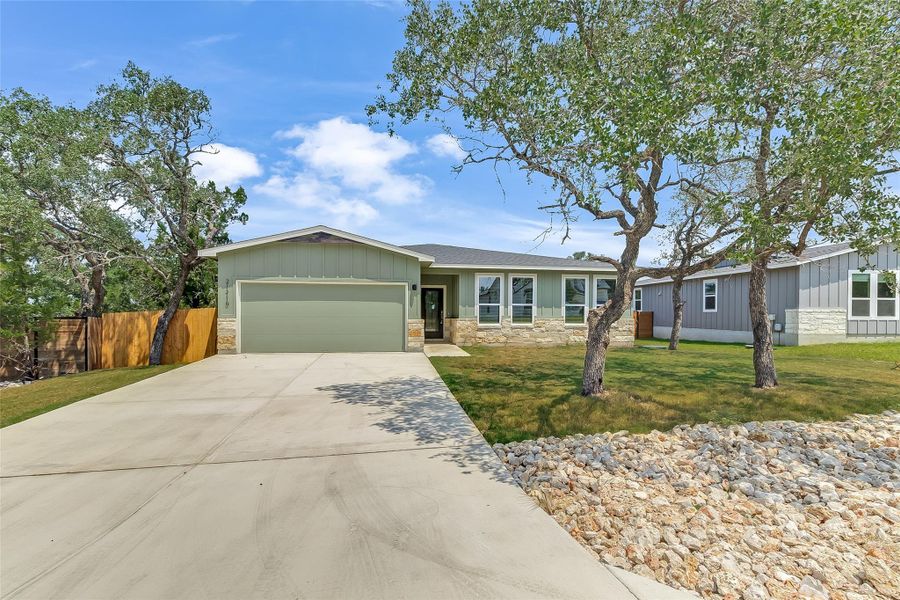 View of front of property featuring concrete driveway, an attached garage, trees, and landscaping View of front of property featuring concrete driveway, an attached garage, trees, and landscaping
