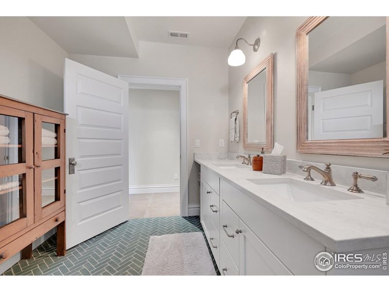 Basement dual sink bathroom with gorgeous herringbone tile floors