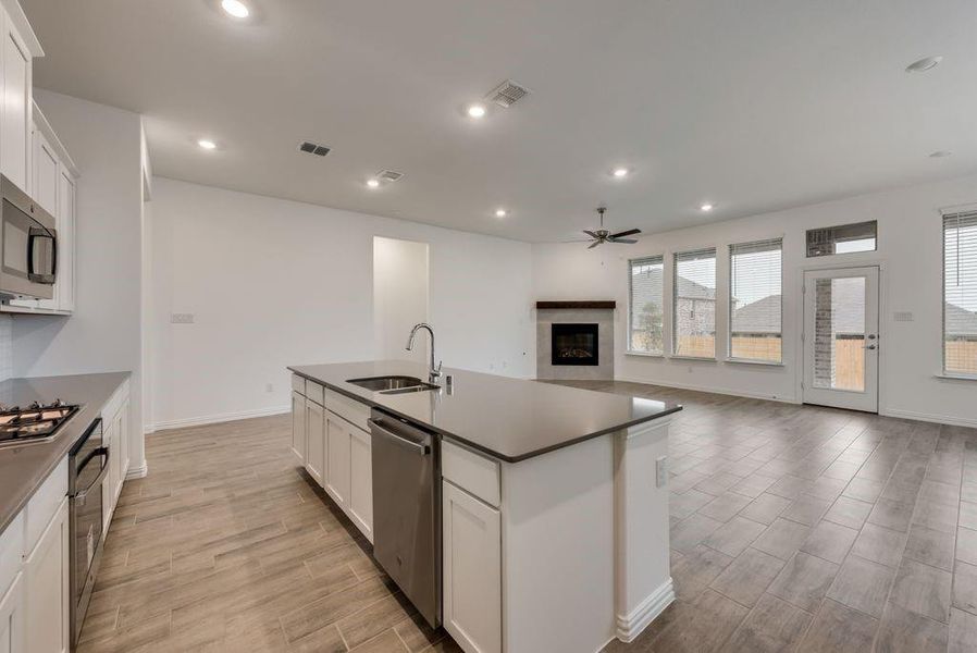 Kitchen featuring light wood-type flooring, a center island with sink, sink, stainless steel appliances, and white cabinets