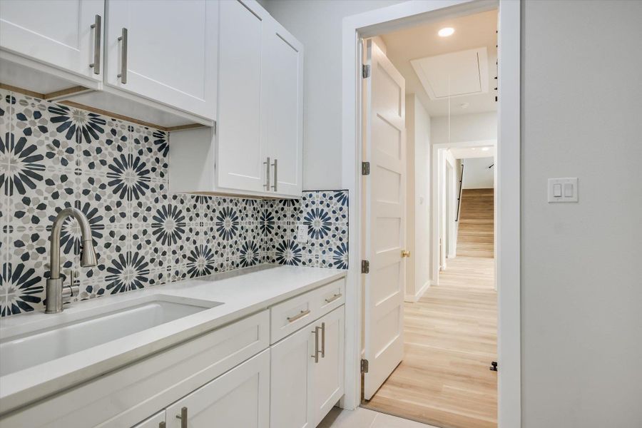 Bar area with white cabinetry, decorative backsplash, light wood-style flooring, light stone counters, and recessed lighting