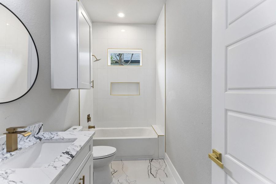 Modern marble-patterned flooring and a vanity with sleek gold fixtures define this well-appointed bathroom.