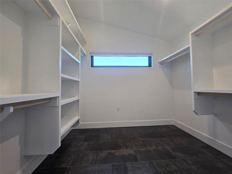 Built-in shelving and custom hanging rods maximize storage space beneath a vaulted ceiling.