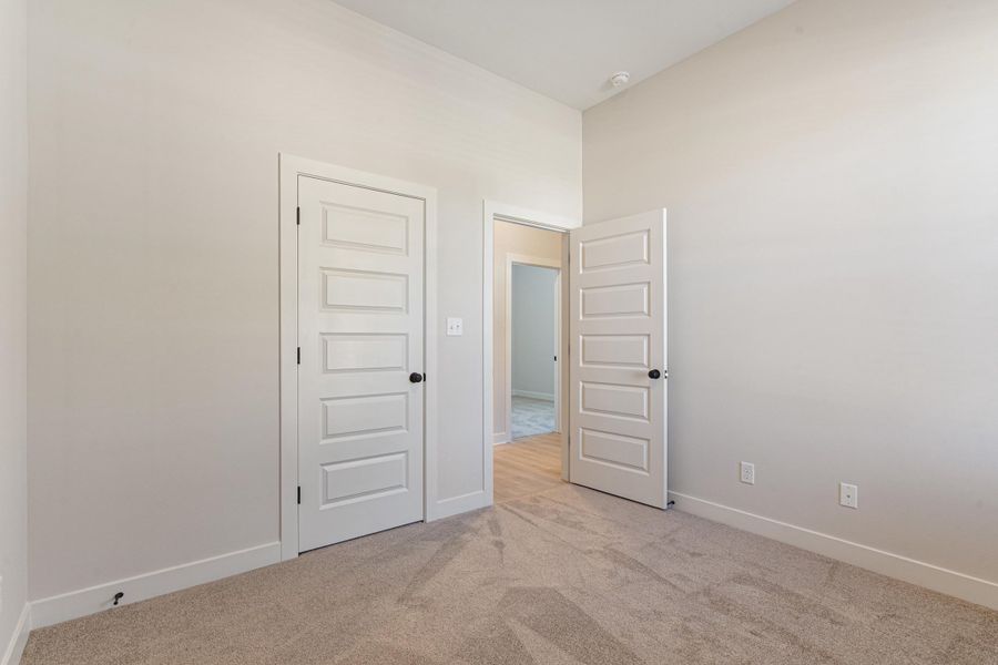 Neutral wall color, carpet flooring, five-panel interior doors, and black door hardware Neutral wall color, carpet flooring, five-panel interior doors, and black door hardware