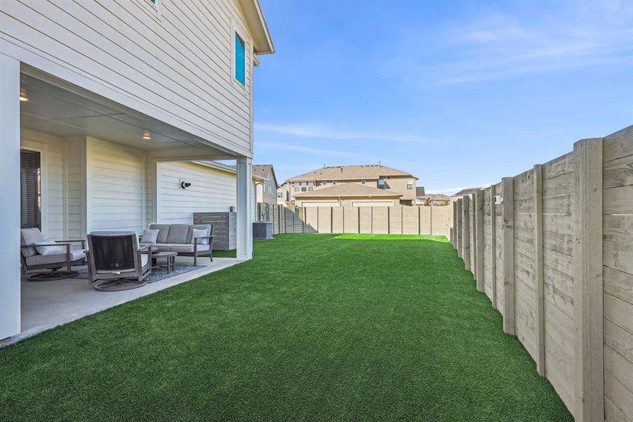 View of yard featuring pet friendly artificial turf and a covered patio area