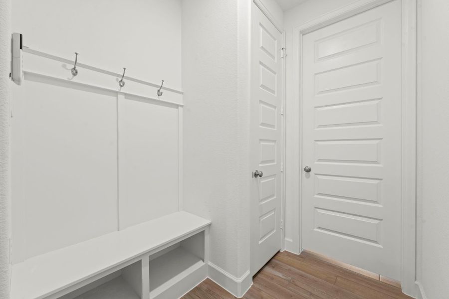 This thoughtfully designed mud area is located off the laundry area and offers a large storage closet, a built-in bench with cubbies below, and three coat or backpack hooks—providing stylish organization for everyday living.