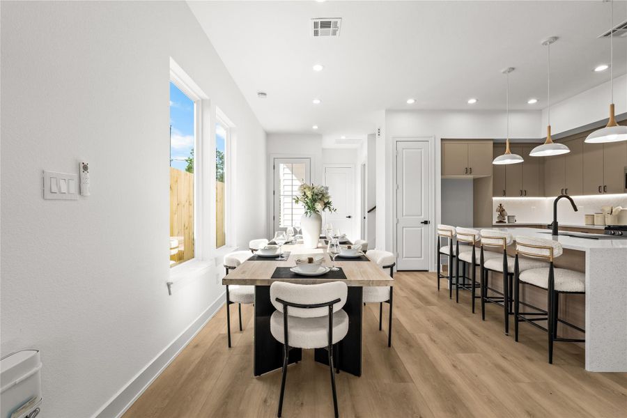 The dining area easily fits a long table and features bright recessed lighting. It sits right off the kitchen, keeping everything connected. Large windows look out into the private, wood-fenced backyard, bringing plenty of natural light into the space.