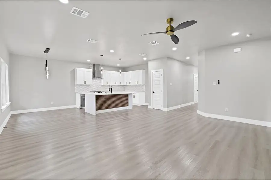 Unfurnished living room with ceiling fan, sink, and light wood-type flooring