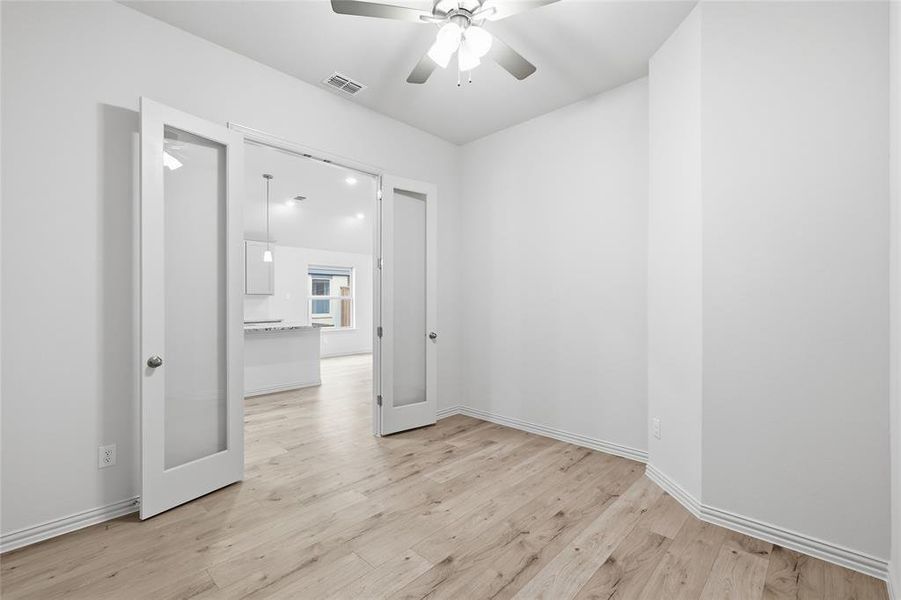 Room with wood-finish flooring, white baseboards, and a ceiling fan Room with wood-finish flooring, white baseboards, and a ceiling fan