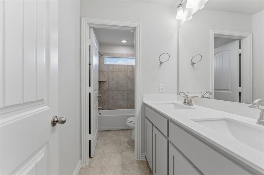 Full bathroom featuring double vanity, shower / bathtub combination, and light tile patterned floors