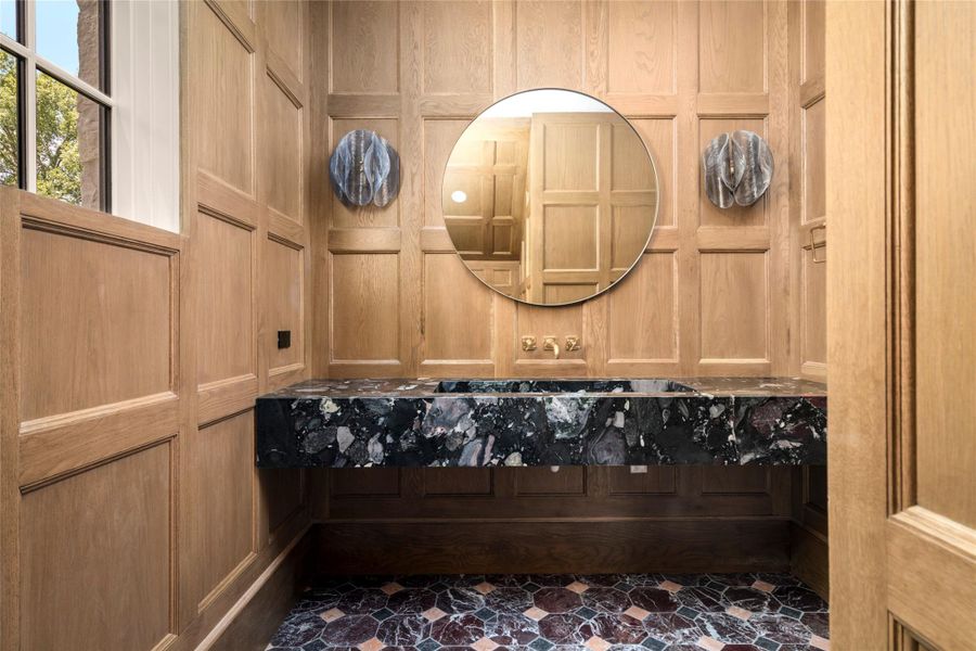 The powder room makes a dramatic statement with floor-to-ceiling white oak paneling and a sculptural floating Palladium Arte marble sink. Waterworks wall-mounted fixtures complete the richly layered space. The powder room makes a dramatic statement with floor-to-ceiling white oak paneling and a sculptural floating Palladium Arte marble sink. Waterworks wall-mounted fixtures complete the richly layered space.