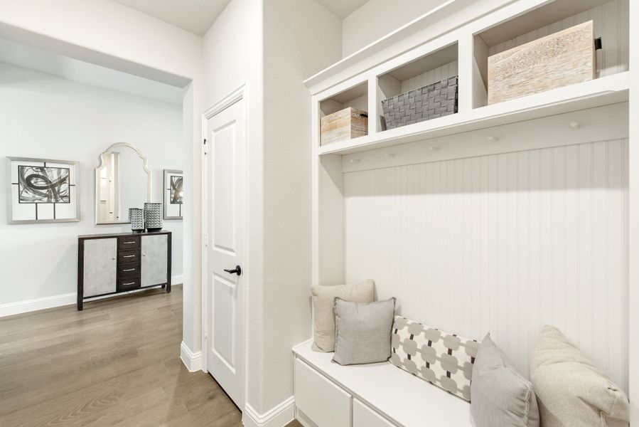 Mudroom with white built-in bench, upper storage shelves, and hallway with console table and mirror Mudroom with white built-in bench, upper storage shelves, and hallway with console table and mirror