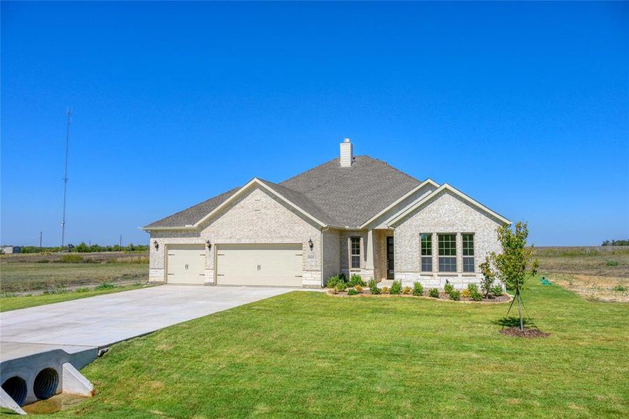 View of front of property featuring a garage and a front lawn