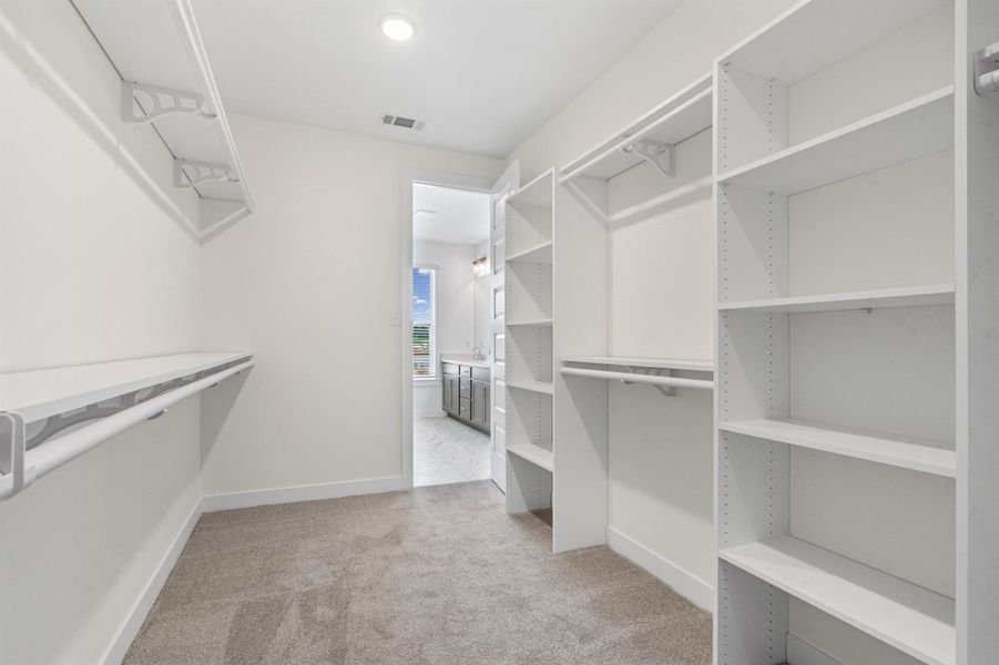 Walk-in closet featuring extensive built-in shelving and hanging rods Walk-in closet featuring extensive built-in shelving and hanging rods