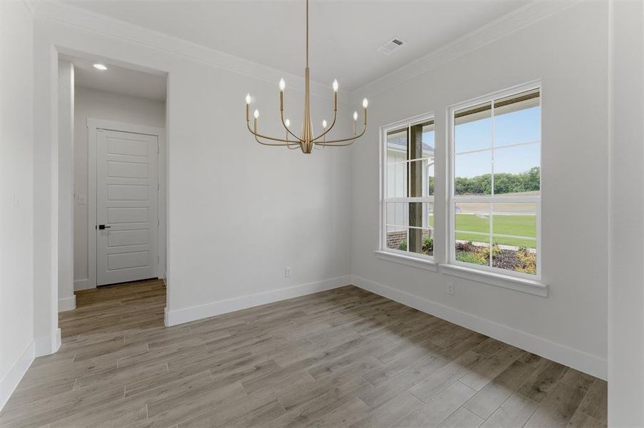 Spacious room featuring wood-finish flooring, a modern chandelier, and dual windows