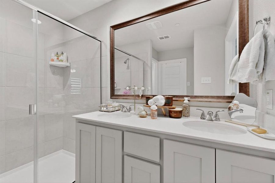 Bathroom featuring a spacious walk-in shower with clear glass enclosure, a double vanity with two undermount sinks, and a large mirror with a wooden frame