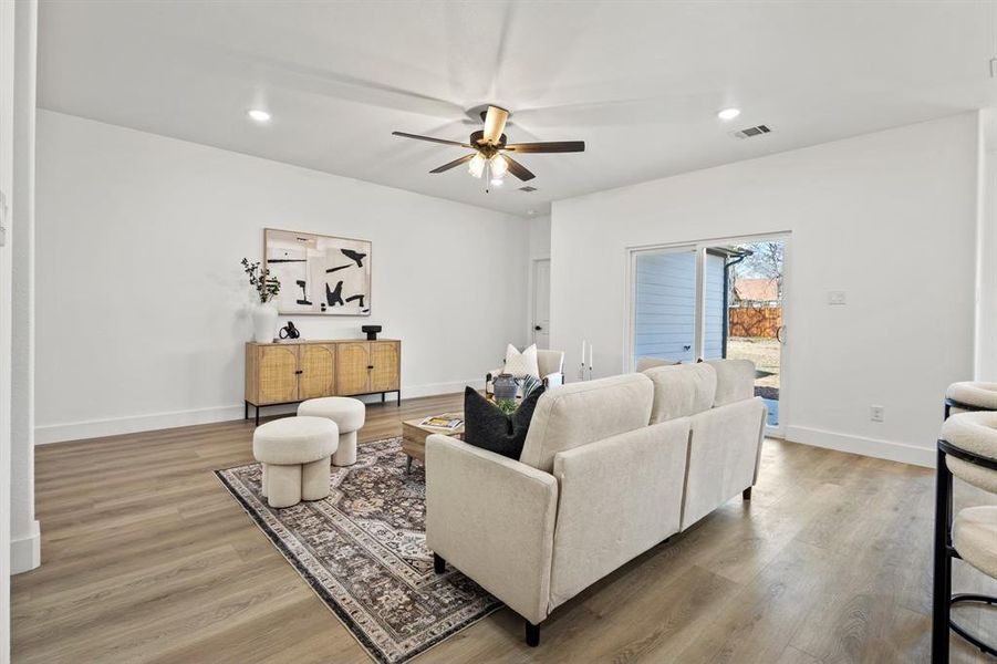 Living room with visible vents, light wood-style flooring, a ceiling fan, recessed lighting, and baseboards